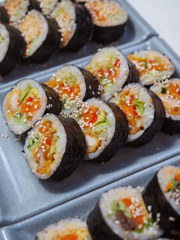 Close-up of traditional Korean kimbap rolls filled with fresh vegetables and sesame seeds.