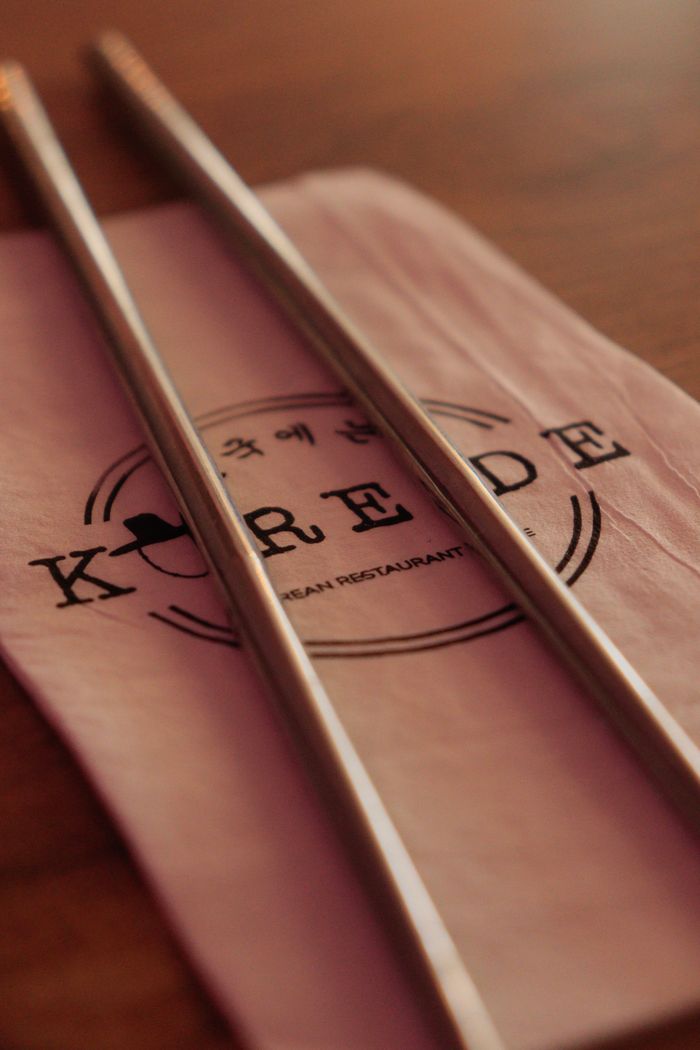 services-03 Close-up of metal chopsticks resting on a napkin with Korean restaurant logo.