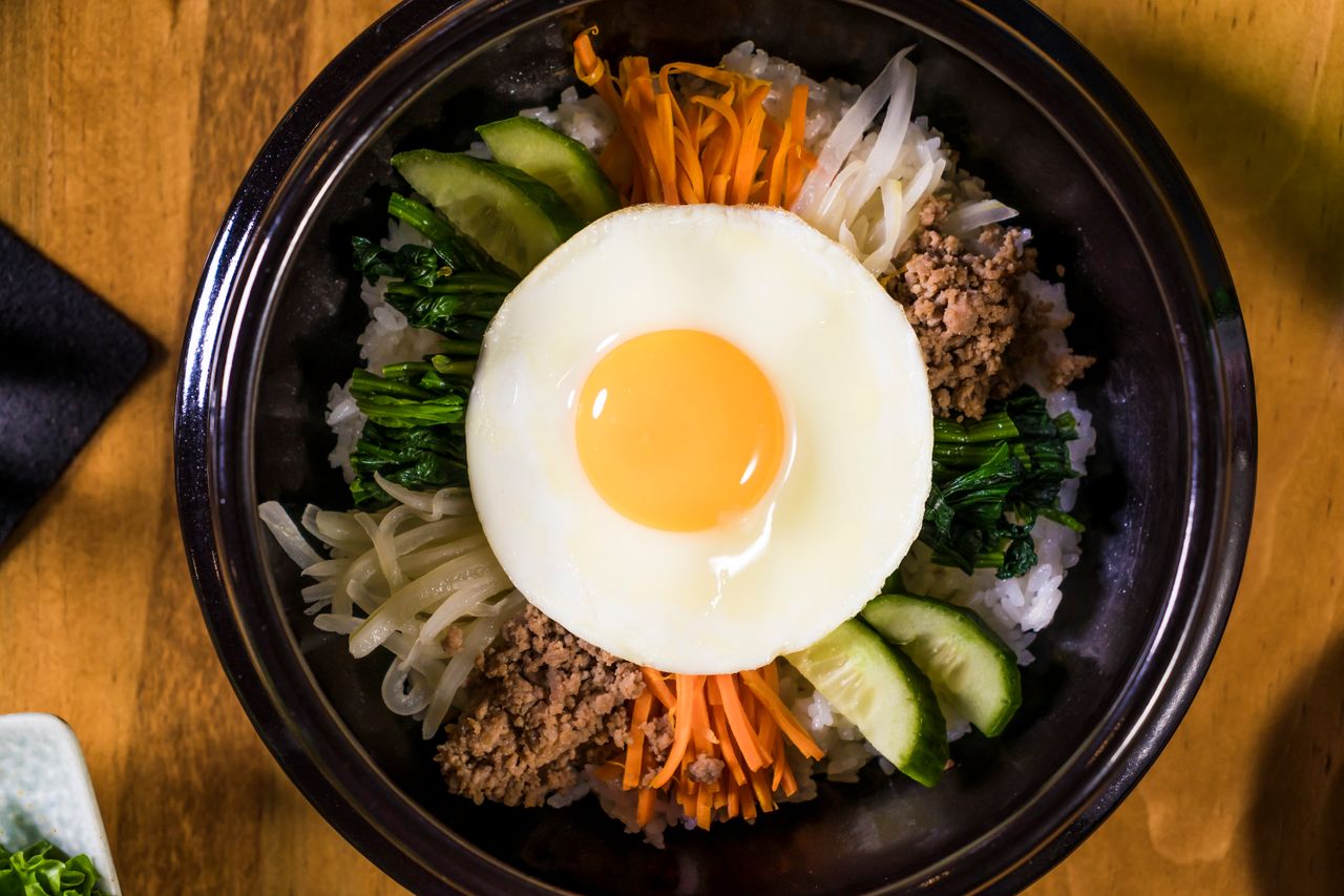 about-us-01 Colorful Korean bibimbap with vegetables and a sunny-side-up egg.