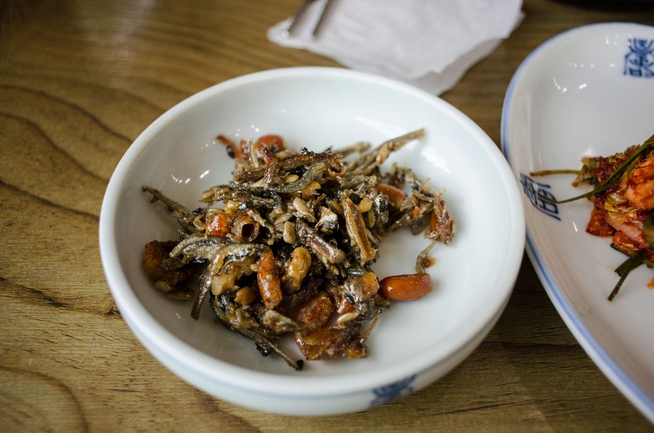 Delicious Korean side dish featuring seasoned anchovies and nuts served in a classic white bowl.